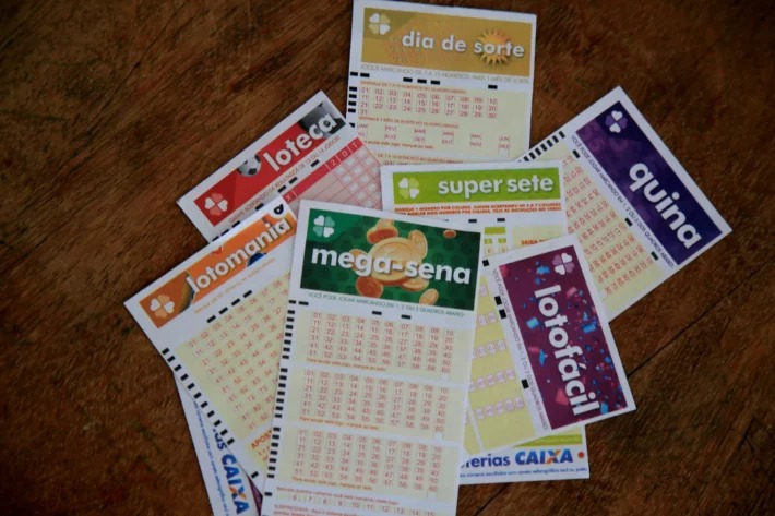 Volantes de aposta da Lotofácil e da Quina sobre uma superfície de madeira.